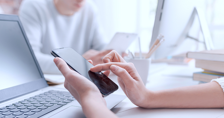 PC前でスマホを触る様子の写真